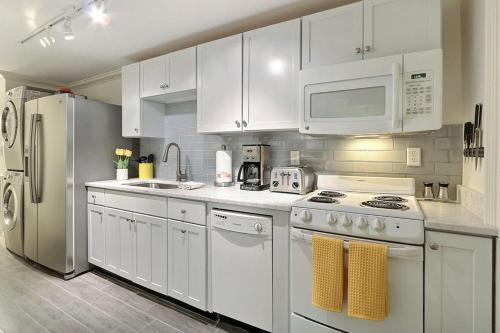 a white kitchen with white appliances and white cabinets at Under The Red Door On Monterey in Savannah