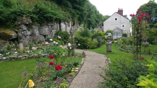 a garden with flowers and a stone wall at Cascades Gardens in Matlock