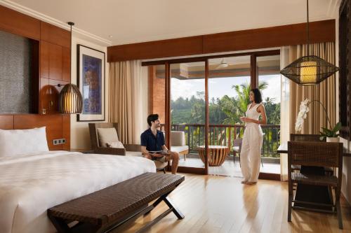 une femme debout dans une chambre d'hôtel avec un homme dans l'établissement Padma Resort Ubud, à Payangan