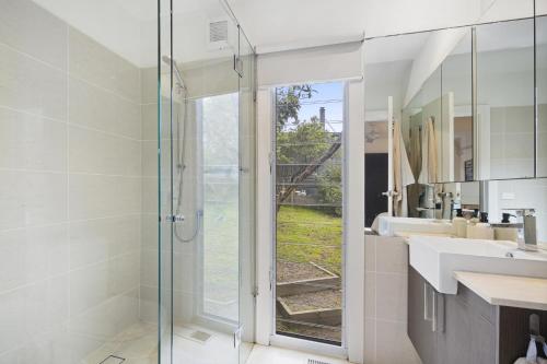 a bathroom with a glass shower and a sink at Nautilus Rise – Panoramic Bay Coastal Views in Tootgarook