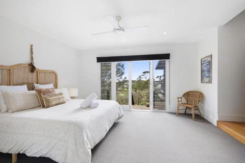 a white bedroom with a bed and a large window at Nautilus Rise – Panoramic Bay Coastal Views in Tootgarook
