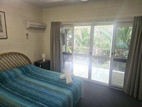a bedroom with a bed and a sliding glass door at Mango Tree Holiday Apartments in Port Douglas