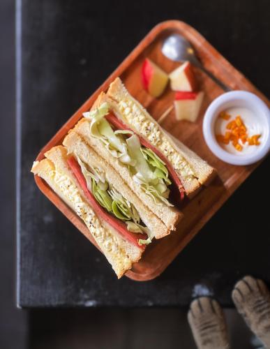 a sandwich on a wooden cutting board with a salad at Tiin Tinn - Rivershore B&B in Taitung City