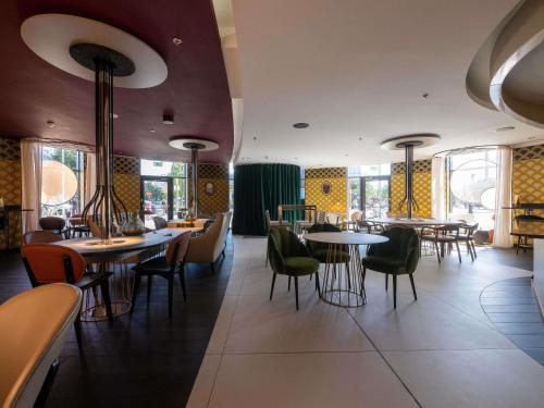 a restaurant with tables and chairs and windows at Pullman Brussels Centre Midi in Brussels