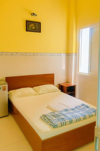 a bed in a room with yellow walls and a window at Nam Dương 1 Hotel in Phan Rang–Tháp Chàm