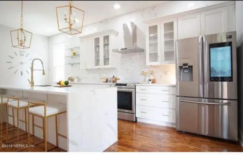 a kitchen with white cabinets and a stainless steel refrigerator at 4 bedroom home- historic-downtown jax- min to UF health and everbank stadium in Jacksonville