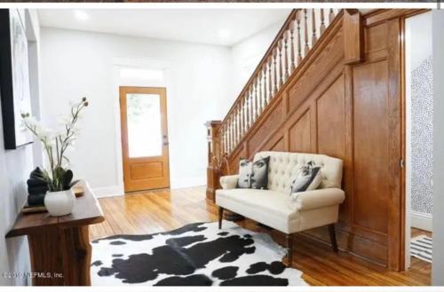 a living room with a chair and a staircase at 4 bedroom home- historic-downtown jax- min to UF health and everbank stadium in Jacksonville