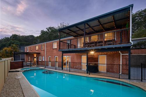 a swimming pool in front of a brick building at Maisonn Hinoki Spacious Holiday Oasis in Daleys Point
