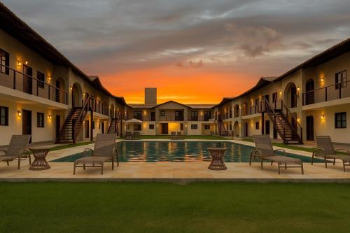 a courtyard with chairs and a pool at sunset at Apartamento no Falésias de Pipa - Veleiros 212 in Pipa