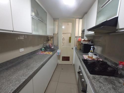 Una cocina con gabinetes blancos y encimera. en Premium Beachfront 3BR Boreal, en Lima