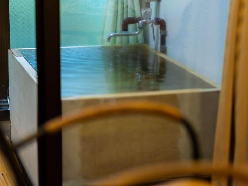 eine Badezimmertheke mit Waschbecken und einem Holzstuhl in der Unterkunft Hotel Casual Euro in Nikko