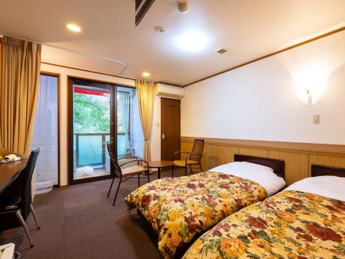 a hotel room with two beds and a table and chairs at Hotel Casual Euro in Nikko