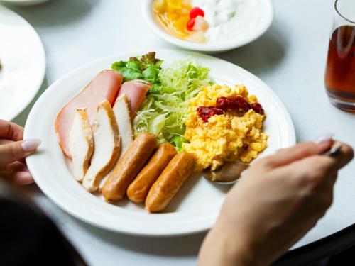 ein weißer Teller mit Essen mit Wurst, Eiern und Salat in der Unterkunft Hotel Casual Euro in Nikko