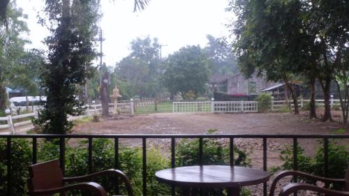 a table and chairs on a balcony with a fence at A-Thip House in Pai