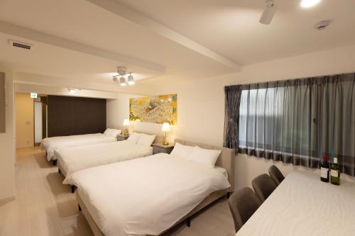 a hotel room with three beds and a window at Star Residence - 博多上呉服 in Fukuoka
