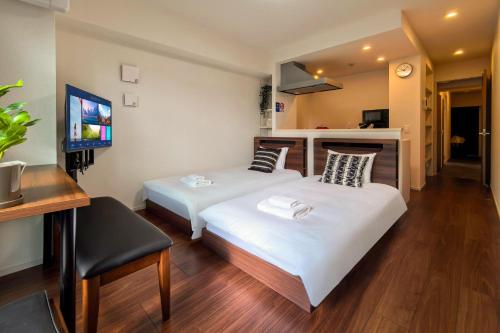 a hotel room with two beds and a television at Poka Premium Kuramae Luxury 2BR Suite Brand-New in Tokyo