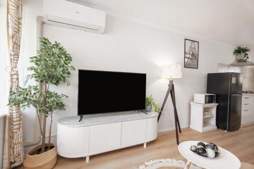 a living room with a flat screen tv on a white wall at Sunny Stay Near Flinders & CBD