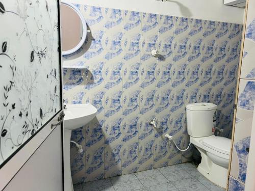 a blue and white bathroom with a toilet and a sink at Nishadi Holiday Inn Kataragama in Kataragama