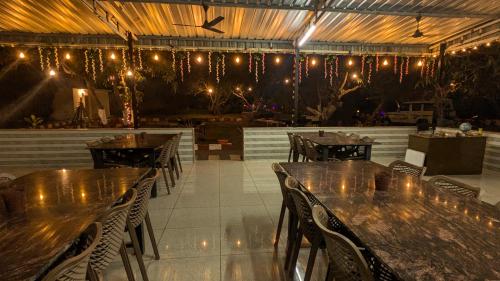 a restaurant with tables and chairs and lights on the ceiling at The Gir Village Stay in Sasan Gir