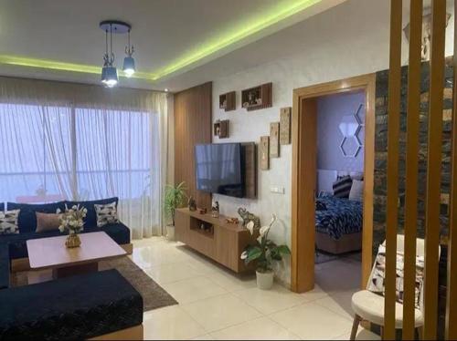 a living room with a blue couch and a bed at Beach Appartement & Résidence Luxury Aourir in Agadir