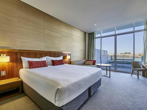 a hotel room with a large bed and a large window at The Sebel Mandurah in Mandurah