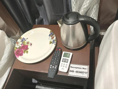 a table with a tea pot and a plate and a remote control at Silk White in Hyderabad