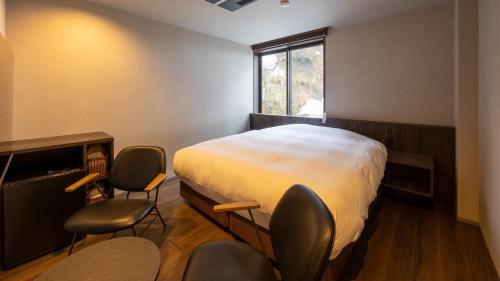 a bedroom with a bed and two chairs in it at Ponshu Hotel Suimu in Tokamachi