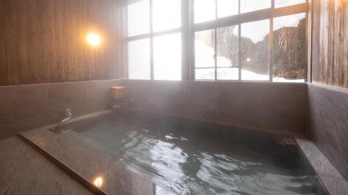 a large bath tub in a room with a window at Ponshu Hotel Suimu in Tokamachi