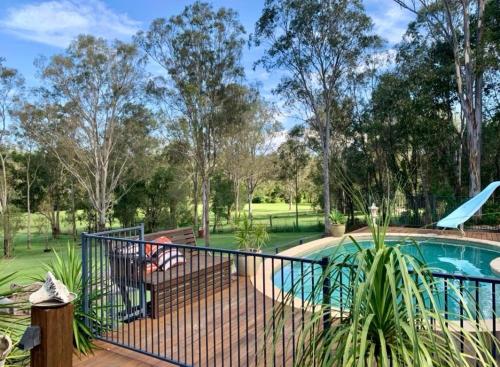 a fence around a swimming pool with trees in the background at Tranquility Ranch by Tiny Away in Wolfdene