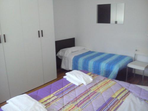 1 dormitorio con 2 camas, armario y silla en Casa Vacanza Holiday en Pieris