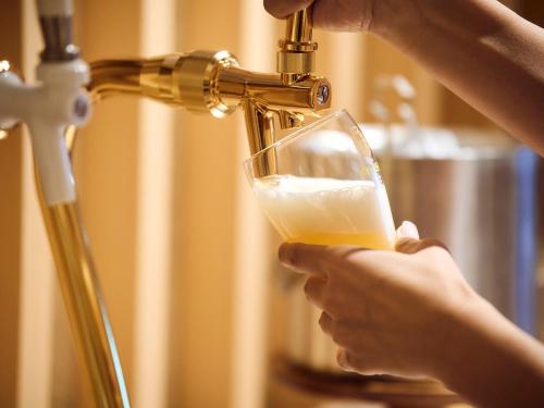 a person holding a glass of wine under a faucet at Hotel SUI Kyoto Kiyomizu in Kyoto
