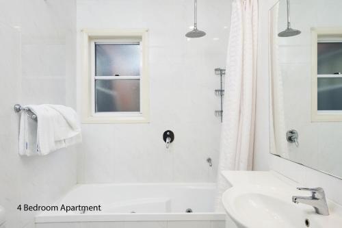 a white bathroom with a tub and a sink at The Charles in Wagga Wagga