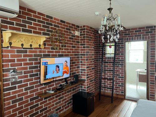 a living room with a brick wall with a television at 墾丁勿忘我城堡莊園 in Hengchun