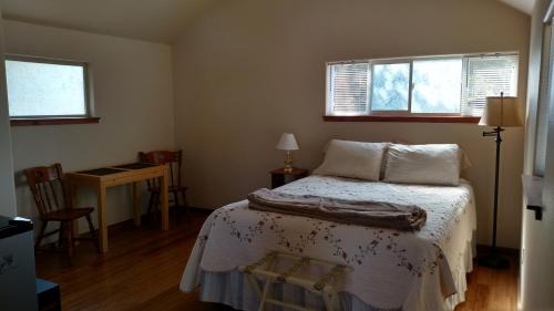 a bedroom with a bed and a desk and two windows at Jones Cabin in Friday Harbor