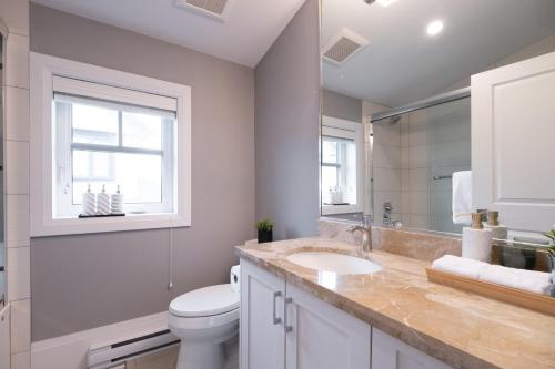 ein Badezimmer mit Toilette und Waschbecken und einem Fenster in der Unterkunft Brand New Stylish 2 bedrooms Suite in Shaughnessy in Vancouver