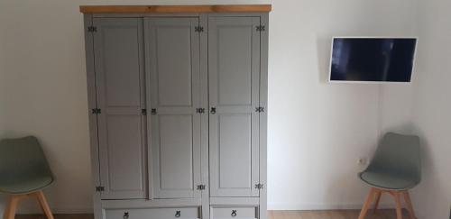 Elle comprend un placard blanc avec 2 chaises et une télévision murale. dans l'établissement Löhner Glück Perfekte Kombination von Geschäftsreise und Familie, à Löhne