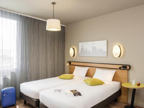 a hotel room with two beds and a table at Aparthotel Adagio Access Paris Massy Gare in Massy