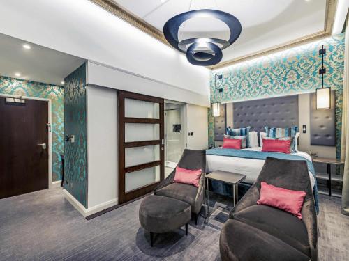 a bedroom with a bed and a couch and chairs at Mercure London Hyde Park Hotel in London