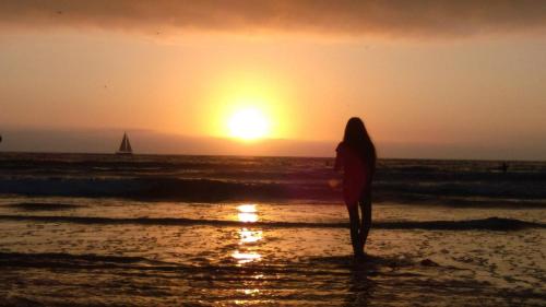 a woman standing on the beach watching the sunset at Morro Crest Inn in Morro Bay