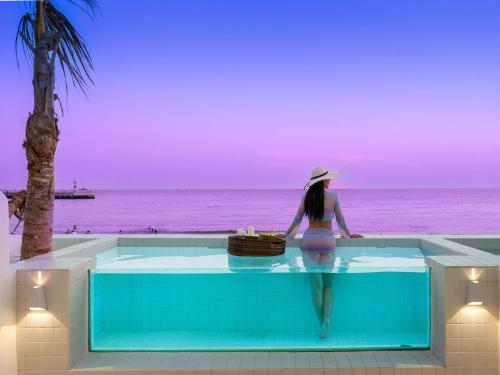 a woman sitting in a swimming pool looking at the ocean at Sanya Nature Reading · Fengbaijing Seaview Hotel in Yamamin