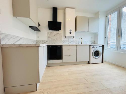 a kitchen with white cabinets and a washer and dryer at Charmant appartement tout confort in Châteaubriant