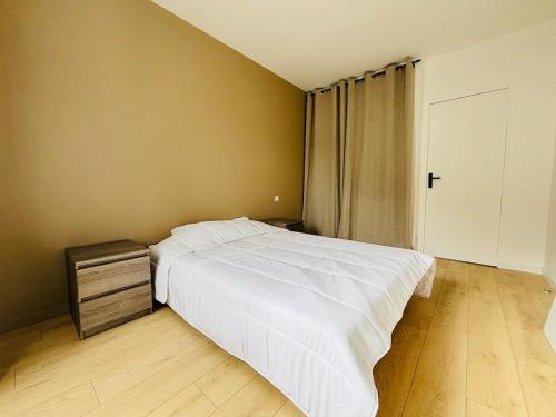 a bedroom with a white bed and a wooden floor at Charmant appartement tout confort in Châteaubriant