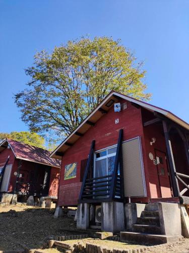 a red building with stairs and a tree in the background at キャンプ&リゾート立山山麓家族旅行村 in Tateyama