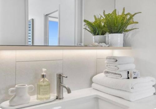 a bathroom with a sink with towels and a mirror at Luxury 2BR 16th Flr Ocean Views in Gold Coast