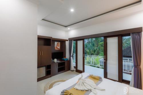a bedroom with a white bed and a balcony at Hanaka Riverside Ubud in Ubud