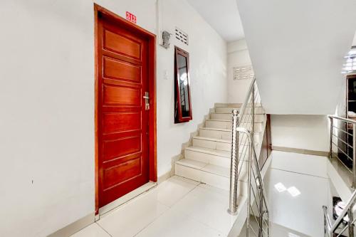a red door in a white hallway with stairs at RedDoorz at Vania Residence Medan in Medan