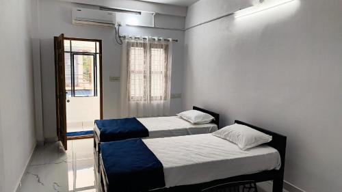 two beds in a room with a window and a door at Pynadath Square in Adūr