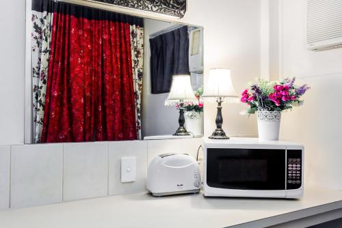 a microwave on a counter with a red curtain at Airport Riverview Motel in Brisbane