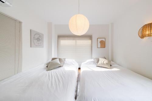 two beds in a room with white walls at KOTOBUKI House - Perfect for Groups - 3 Bedrooms, 3 Baths in Tokyo