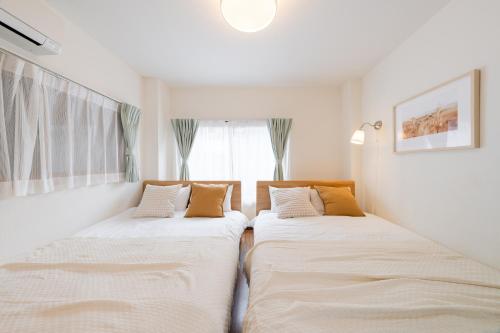 two beds sitting next to each other in a bedroom at KOTOBUKI House - Perfect for Groups - 3 Bedrooms, 3 Baths in Tokyo